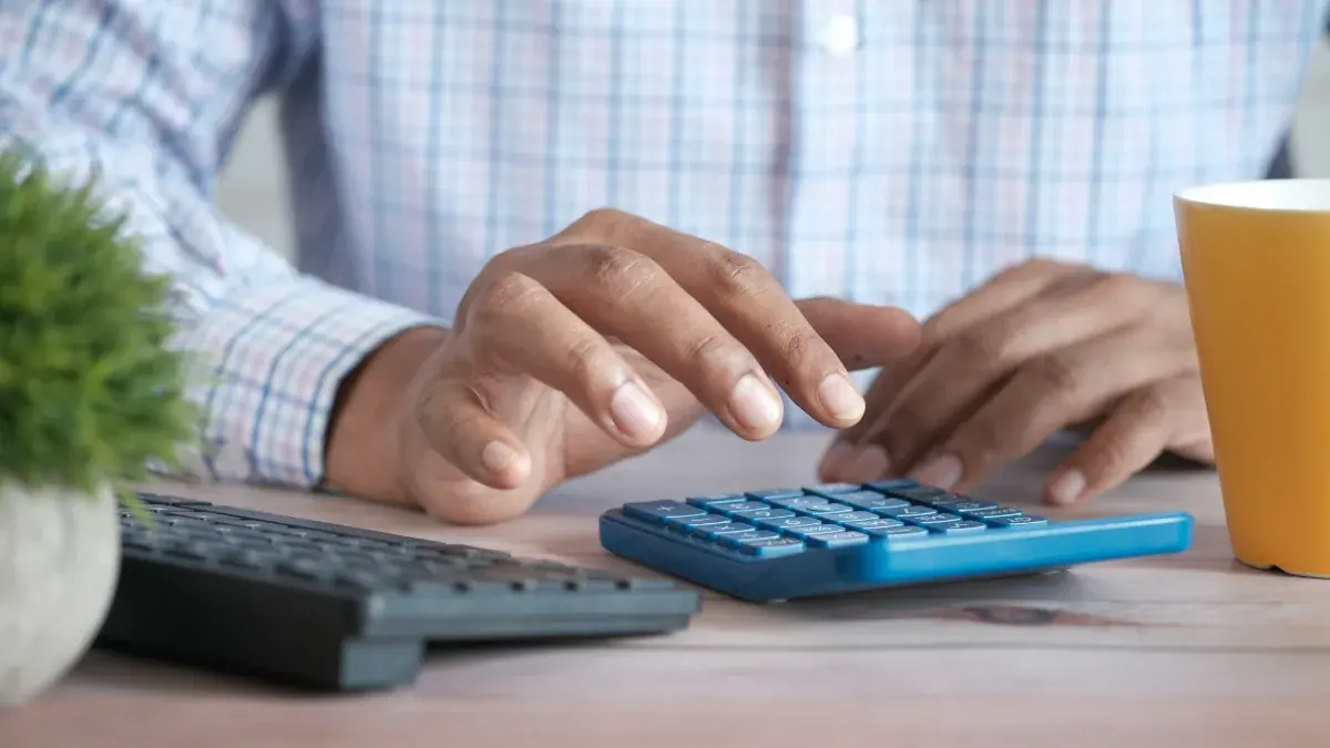 Person using a calculator at a desk to plan a home buying budget
