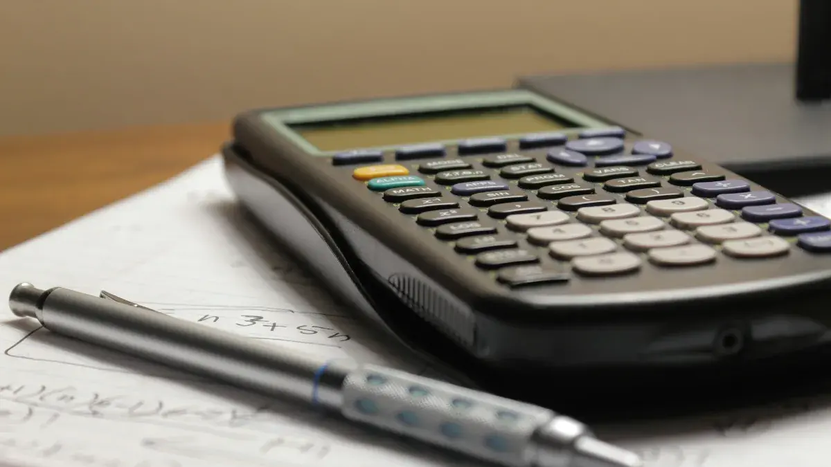 Calculator and pen resting on a page of mortgage calculations